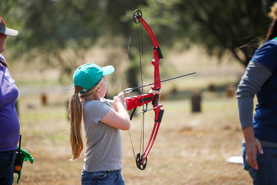 A young Girl Scout pulls back on a bow and prepares to fire an arrow at the 2019 Outdoor Adventure Campout. Photo courtesy of Girl Scouts Heart of Central California